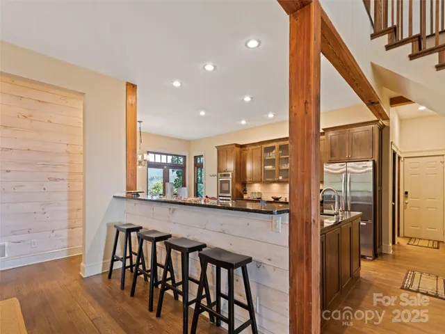 a kitchen with stainless steel appliances granite countertop a table chairs sink and wooden floor