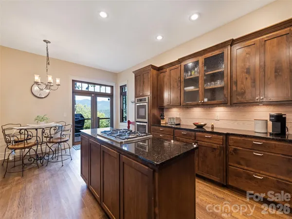 a kitchen with stainless steel appliances granite countertop a sink a stove and wooden cabinets