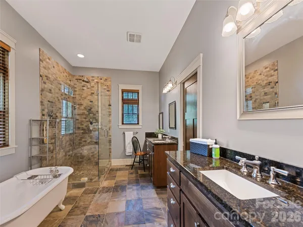 a spacious bathroom with a granite countertop sink a toilet a mirror a bathtub and shower