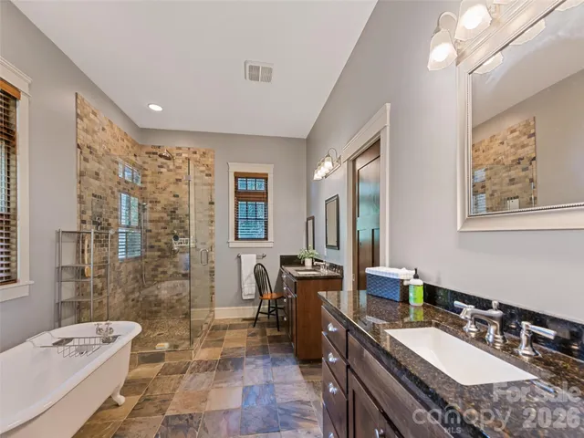 a spacious bathroom with a granite countertop sink a toilet a mirror a bathtub and shower