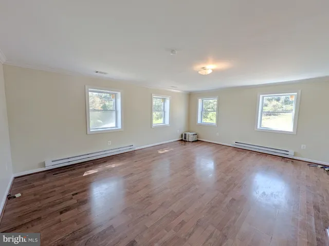 a view of a big room with wooden floor and windows