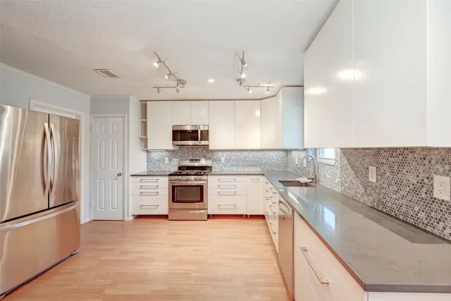 a large kitchen with stainless steel appliances a refrigerator and a stove top oven