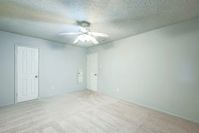 a view of an empty room with a chandelier fan