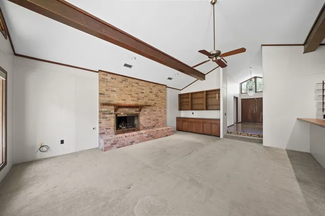 a view of an empty room with a fireplace and a window