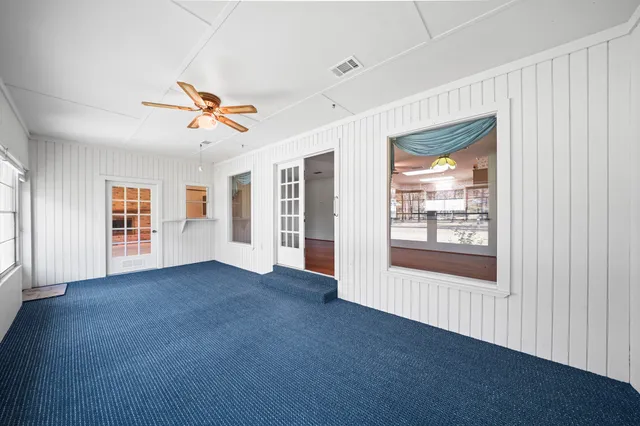 a view of n empty room with window and a kitchen