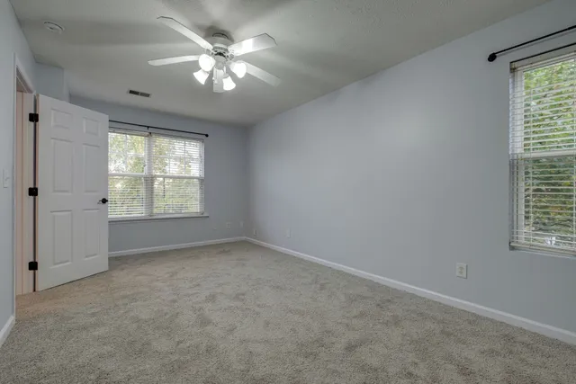 an empty room with windows and chandelier fan