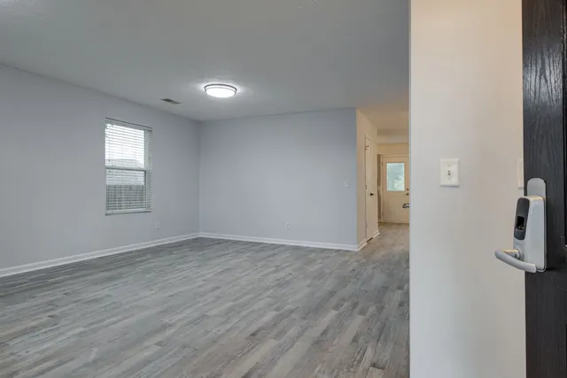 a view of an empty room with wooden floor and a window