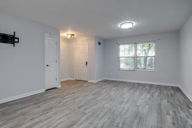 an empty room with wooden floor and windows