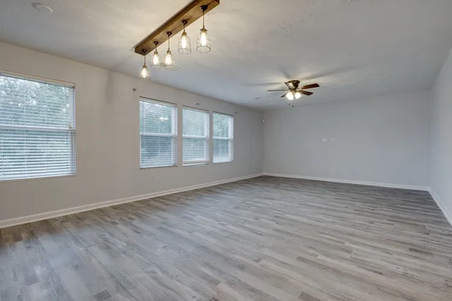a view of an empty room with a window and wooden floor