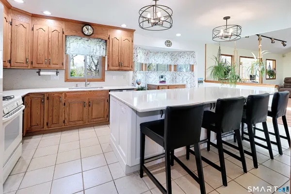 a kitchen with stainless steel appliances granite countertop a sink a stove a dining table and chairs with wooden floor
