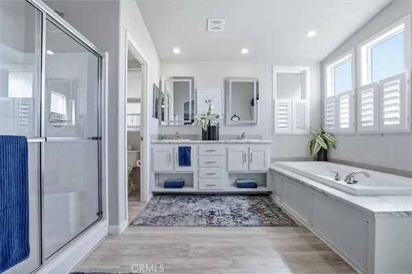 a bathroom with a double vanity sink a mirror a bathtub and window