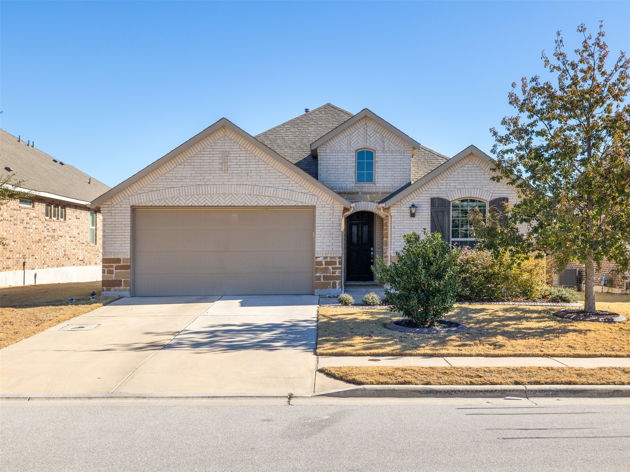 French country home featuring brick siding, concrete driveway, and an attached garage