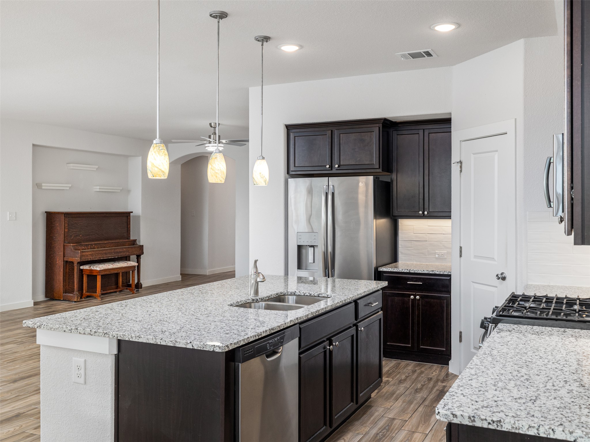 6856 Catania Loop Round Rock, TX 78665 - Photo 12 of 30 Kitchen featuring pendant lighting, ceiling fan, stainless steel appliances, a kitchen island with sink, and light stone counters