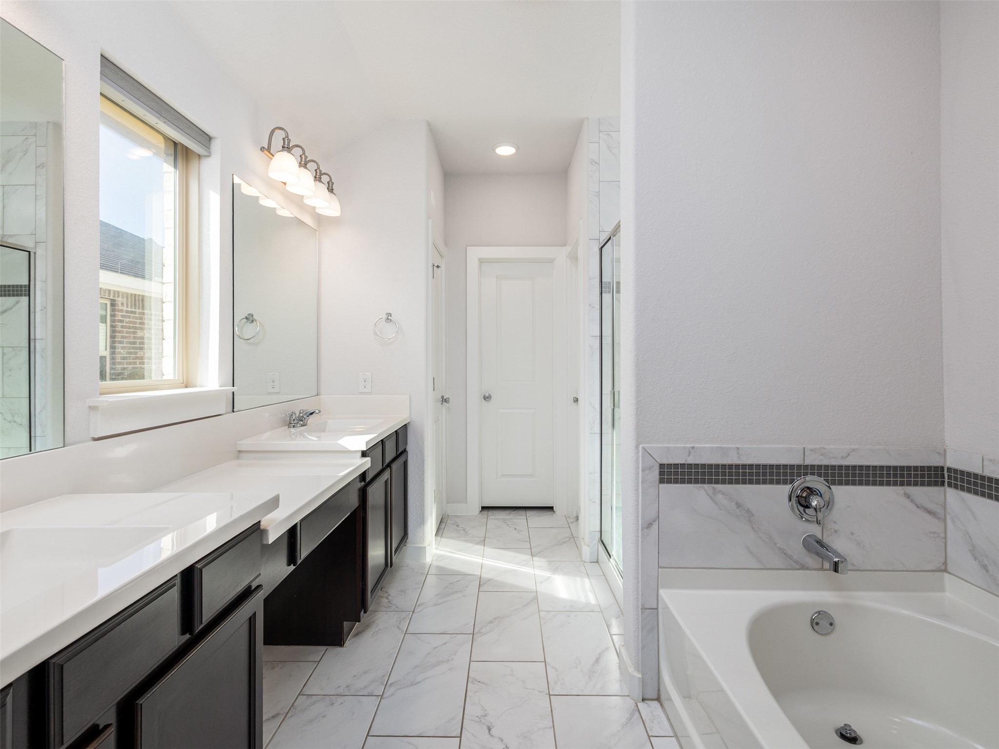 6856 Catania Loop Round Rock, TX 78665 - Photo 16 of 30 Bathroom featuring double vanity, light marble finish floors, a garden tub, and a stall shower