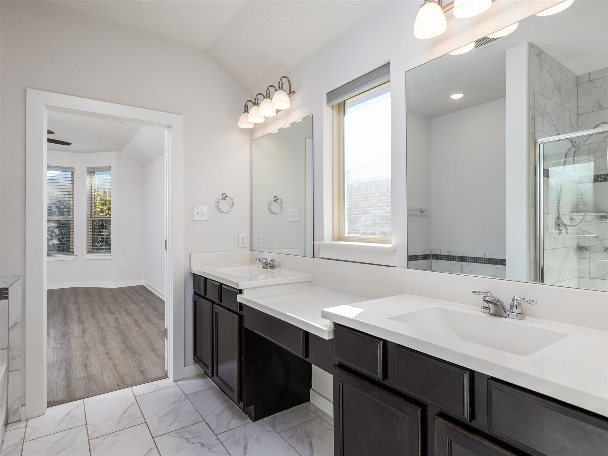 6856 Catania Loop Round Rock, TX 78665 - Photo 17 of 30 Bathroom featuring double vanity, a shower stall, plenty of natural light, light marble finish floors, and lofted ceiling