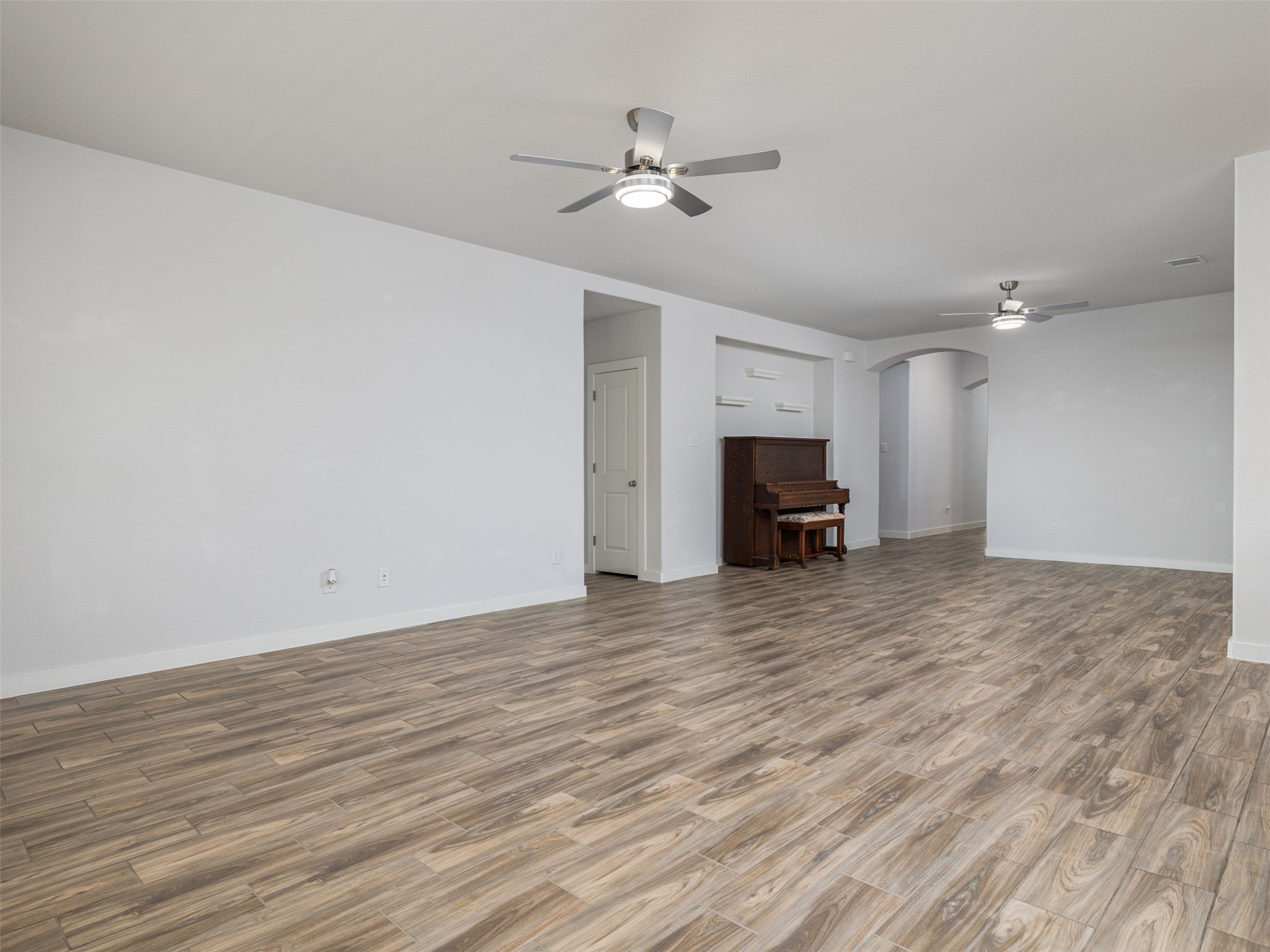 6856 Catania Loop Round Rock, TX 78665 - Photo 9 of 30 Unfurnished living room featuring ceiling fan, arched walkways, and wood finished floors