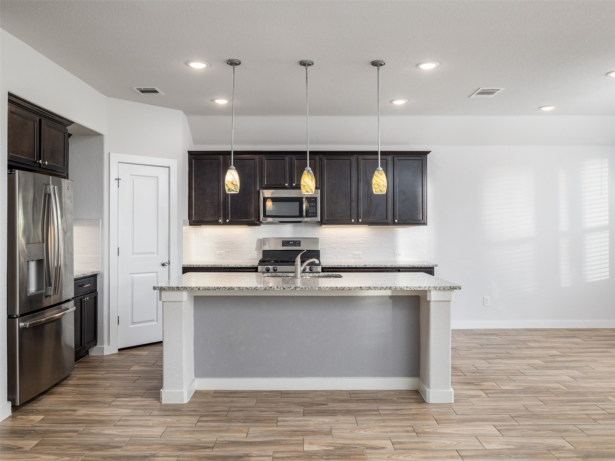 6856 Catania Loop Round Rock, TX 78665 - Photo 10 of 30 Kitchen featuring wood tiled floors, stainless steel appliances, and light stone countertops
