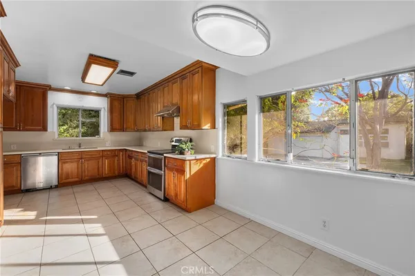 a kitchen with stainless steel appliances a sink a stove a refrigerator cabinets and a window