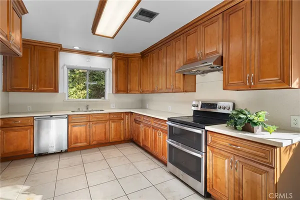 a kitchen with stainless steel appliances granite countertop a sink dishwasher stove and refrigerator with wooden cabinets