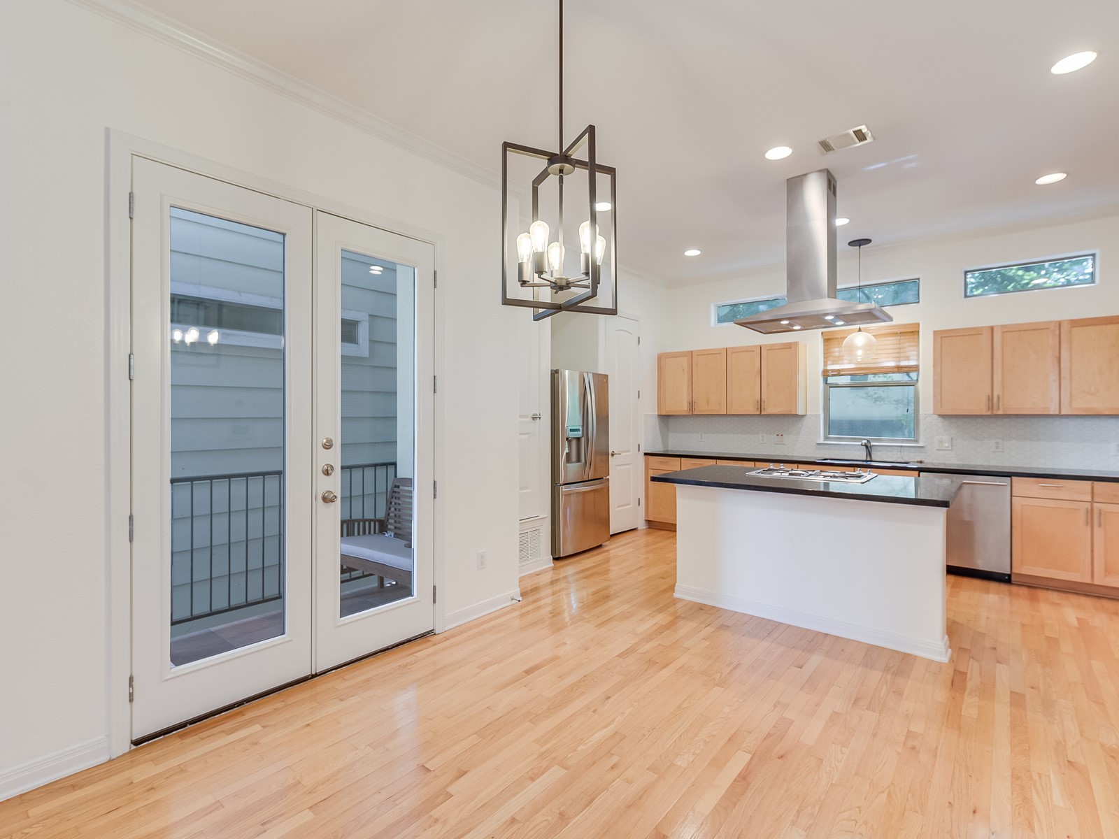 1115 Kinney Avenue, Unit 9 Austin, TX 78704 - Photo 9 of 19 Kitchen with visible vents, island range hood, dark countertops, stainless steel appliances, and light brown cabinetry