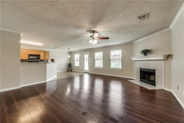 a view of an empty room with wooden floor and a kitchen