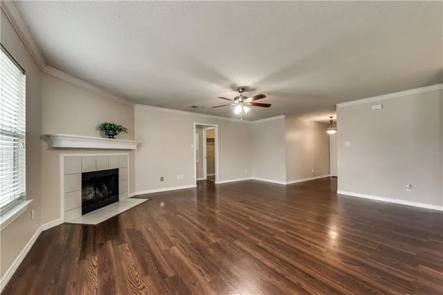 an empty room with wooden floor fireplace and windows