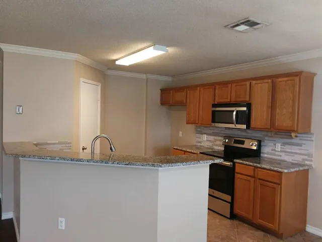 a kitchen with stainless steel appliances granite countertop a sink a stove a microwave a refrigerator a sink and dishwasher