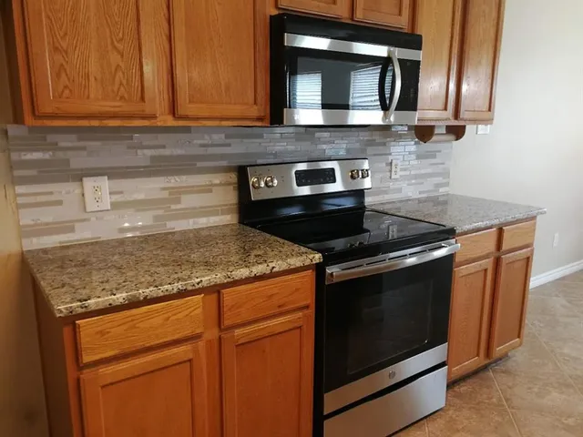 a kitchen with granite countertop stove top oven microwave and cabinets