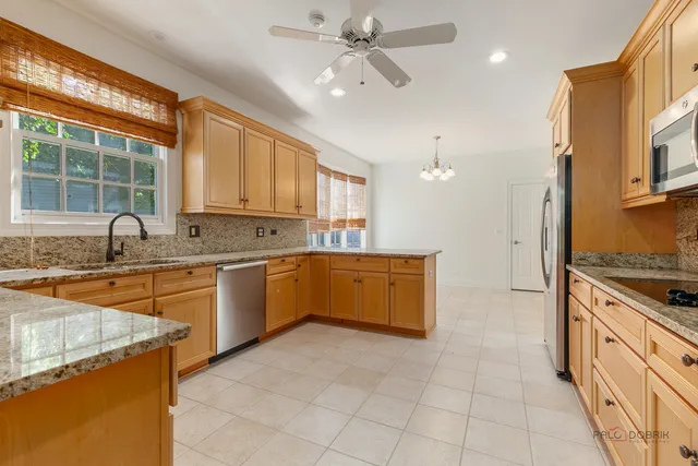 a large kitchen with stainless steel appliances granite countertop a stove a sink and a refrigerator