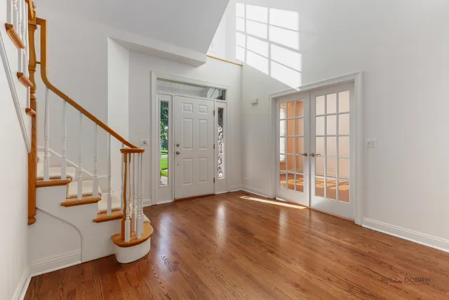 a view of an empty room with wooden floor and fan