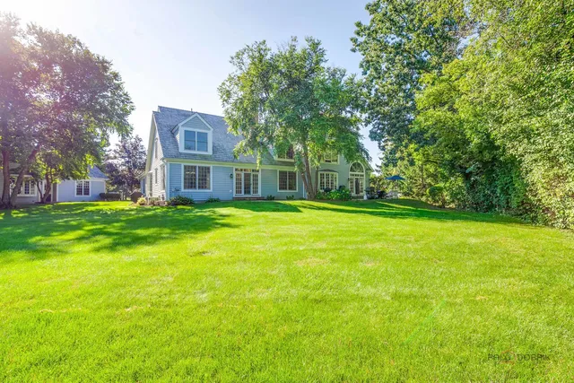 a view of a house with a big yard and large trees