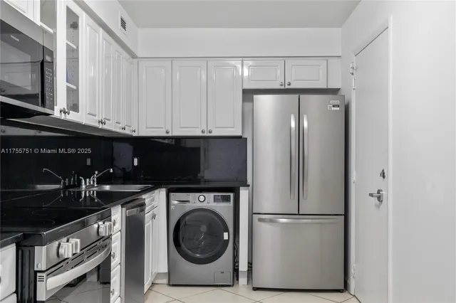 a kitchen with stainless steel appliances granite countertop a refrigerator a washer and dryer