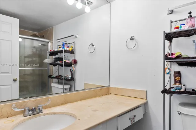 a bathroom with a granite countertop sink a mirror and shower