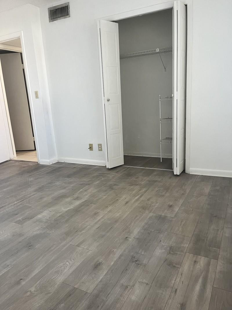 280 Racquet Club Road, Unit 206 Weston, FL 33326 - Photo 4 of 6 an empty room with wooden floor and mirror