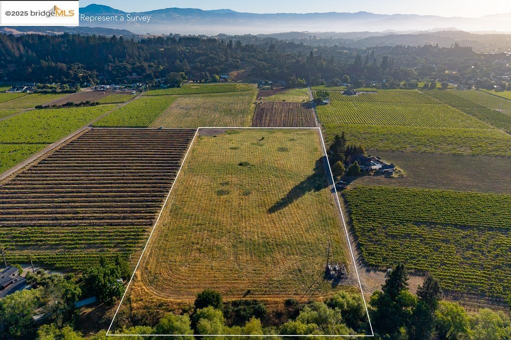 838 Dry Creek Road Healdsburg, CA 95448 - Photo 10 of 22 Aerial view of sparsely populated area featuring property parcel outlined, a mountain backdrop, and abundant farmland