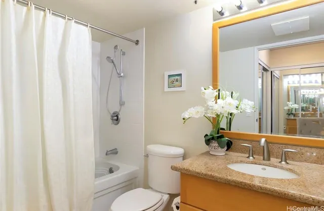 a bathroom with a granite countertop sink a toilet and shower