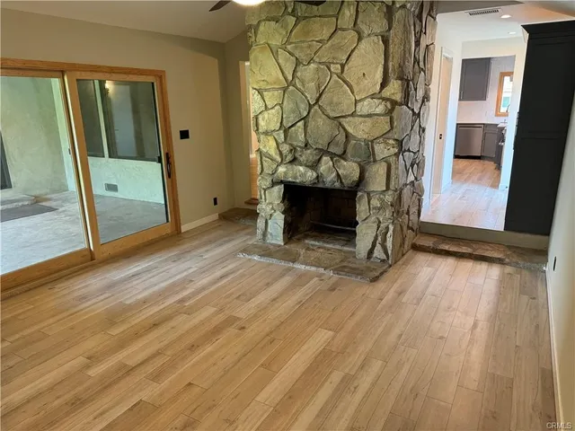 a view of a livingroom with wooden floor and a fireplace