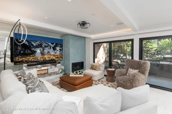 a living room with furniture a flat screen tv and a floor to ceiling window