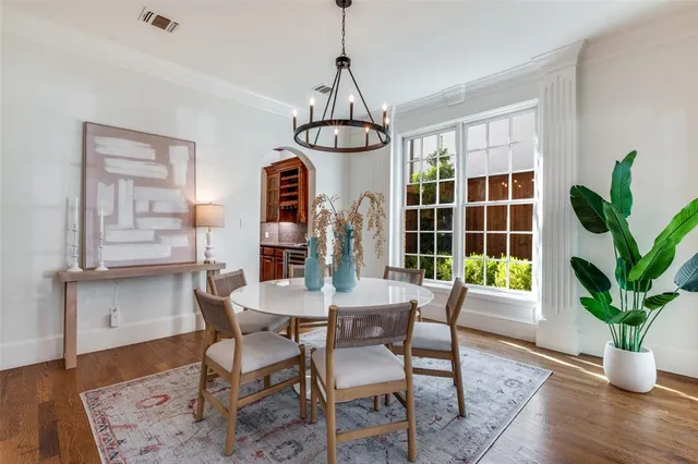 a dining room with wooden floor a chandelier a wooden table and chairs