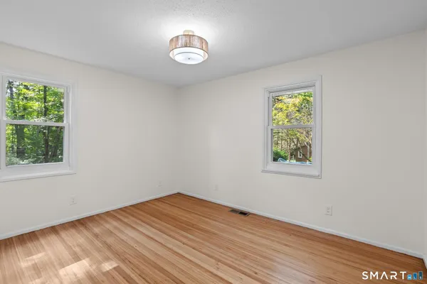 a view of empty room with window and wooden floor