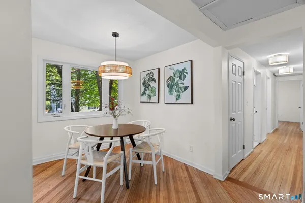 a dining room with wooden floor a chandelier a wooden table and chairs