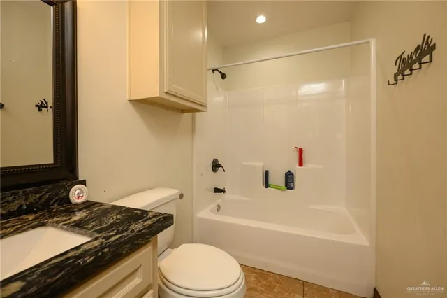 a bathroom with a granite countertop bathtub shower sink vanity and toilet