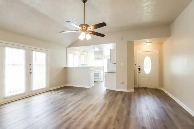 a view of an empty room with window and wooden floor