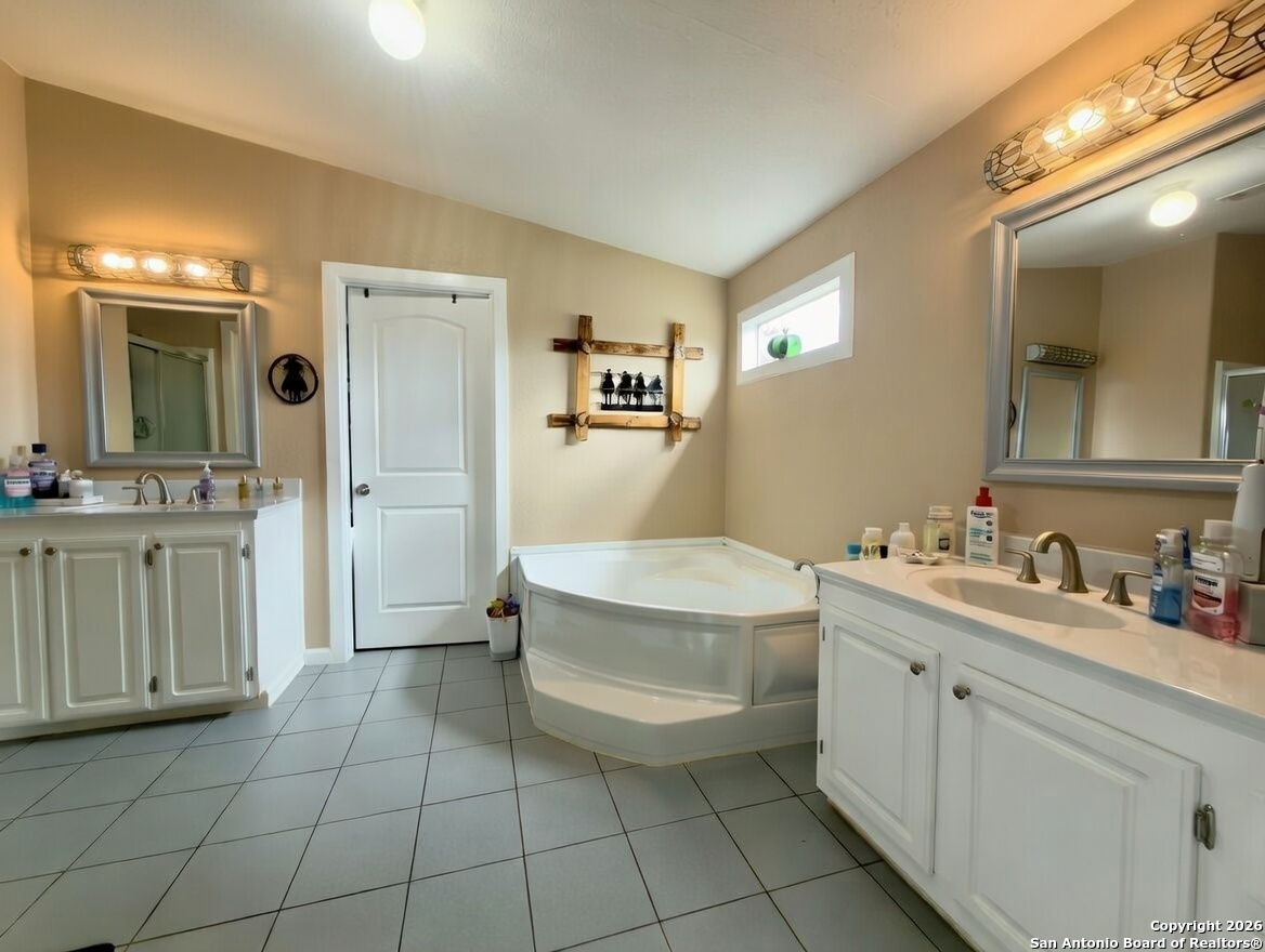 946 Frontier Lane Bandera, TX 78003 - Photo 22 of 49 a spacious bathroom with a double vanity sink a mirror and a bathtub