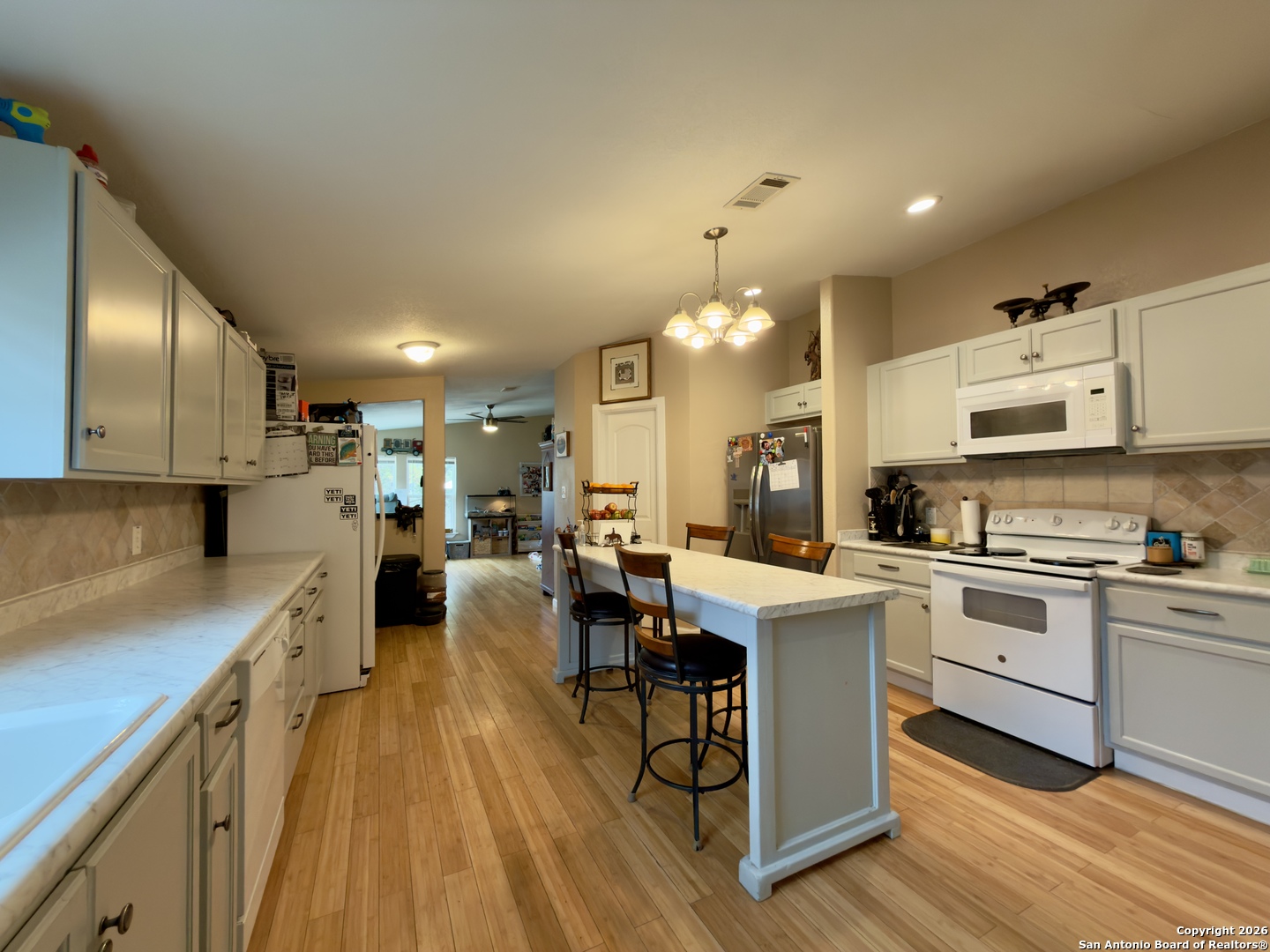 946 Frontier Lane Bandera, TX 78003 - Photo 23 of 48 a large kitchen with cabinets chairs and wooden floor