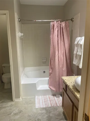 a bathroom with a granite countertop bathtub shower and toilet