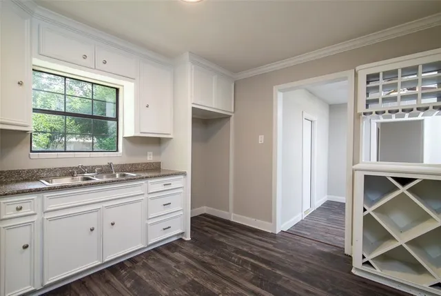a kitchen with stainless steel appliances cabinets wooden floor and a window