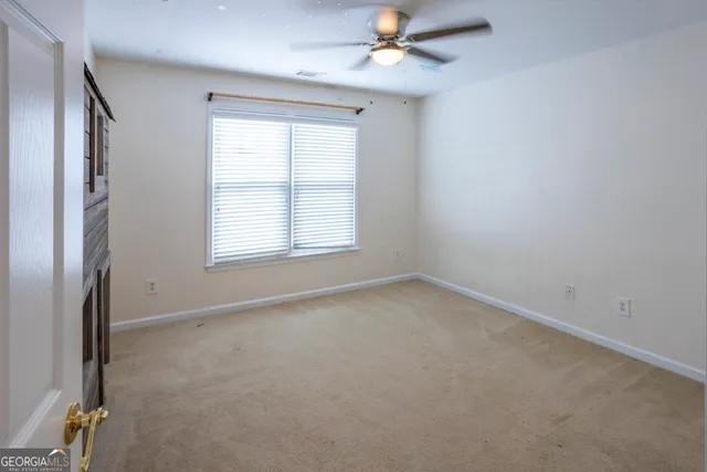 an empty room with a window and a fan