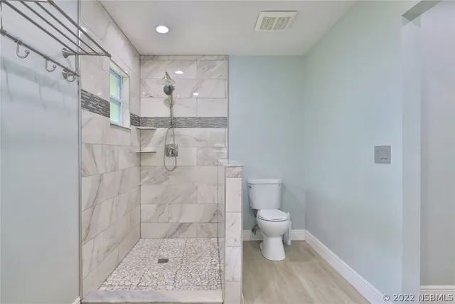 a walk in closet with wooden floor