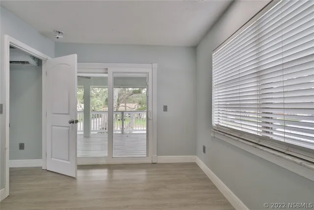 a view of a room with wooden floor a ceiling fan and windows